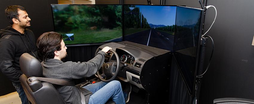 Two students working on driving simulator.